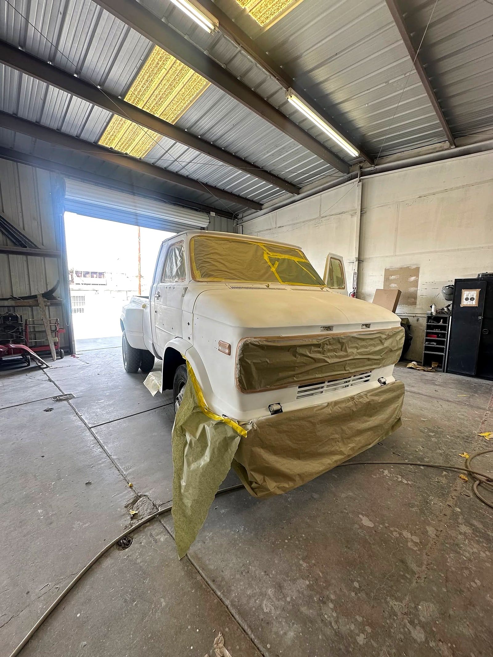 White Chevy Van 30 HD dually pickup with its front end masked inside the shop