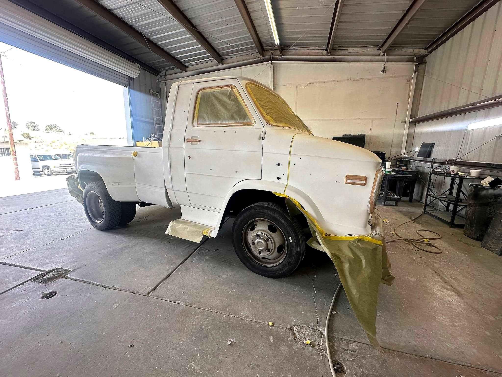 The Chevy Van 30 HD dually masked with paper and tape, side front view, inside the shop