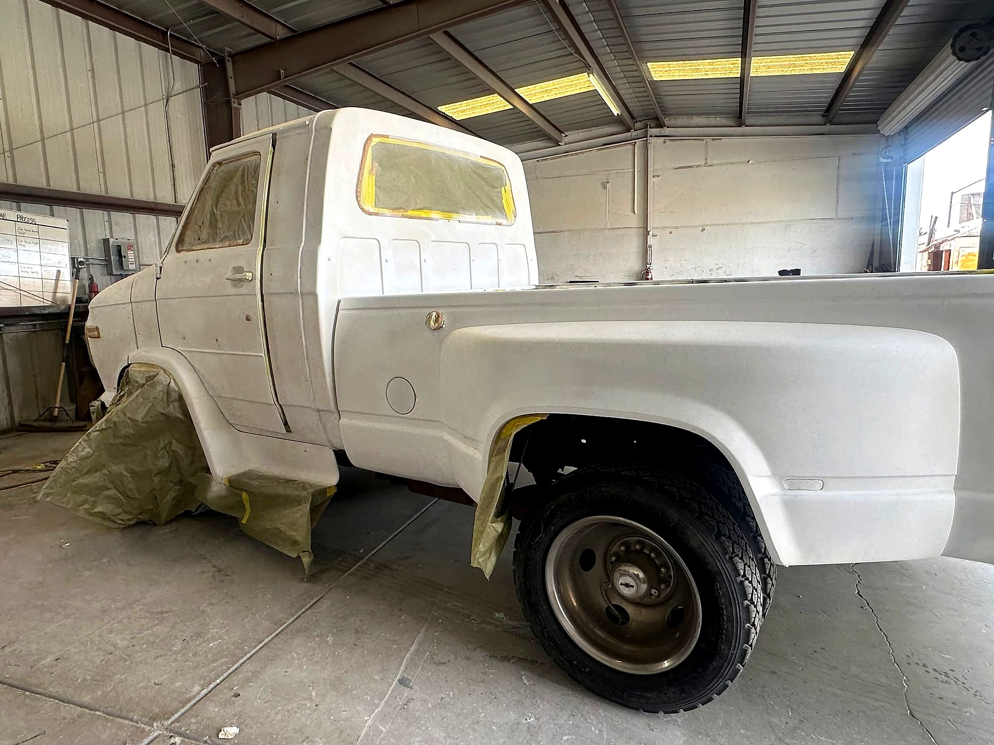 The Chevy Van 30 HD dually, bed side, masked inside the shop
