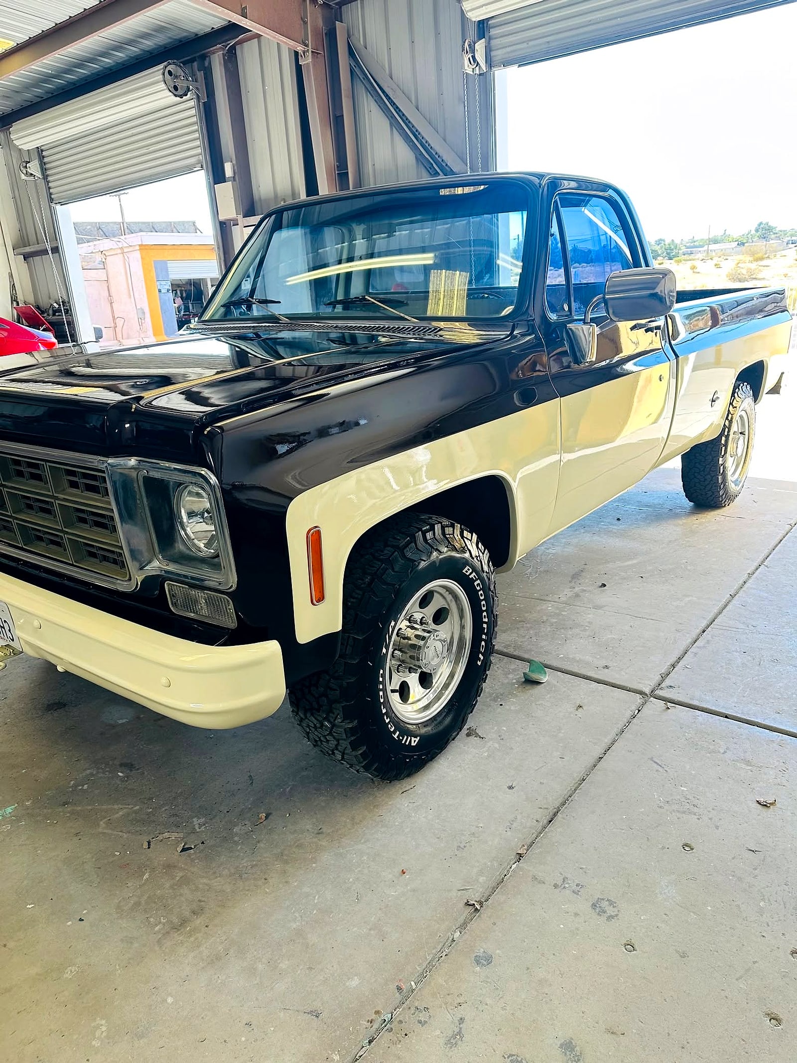 The two-tone square-body Chevy from the front three-quarter, inside the bay