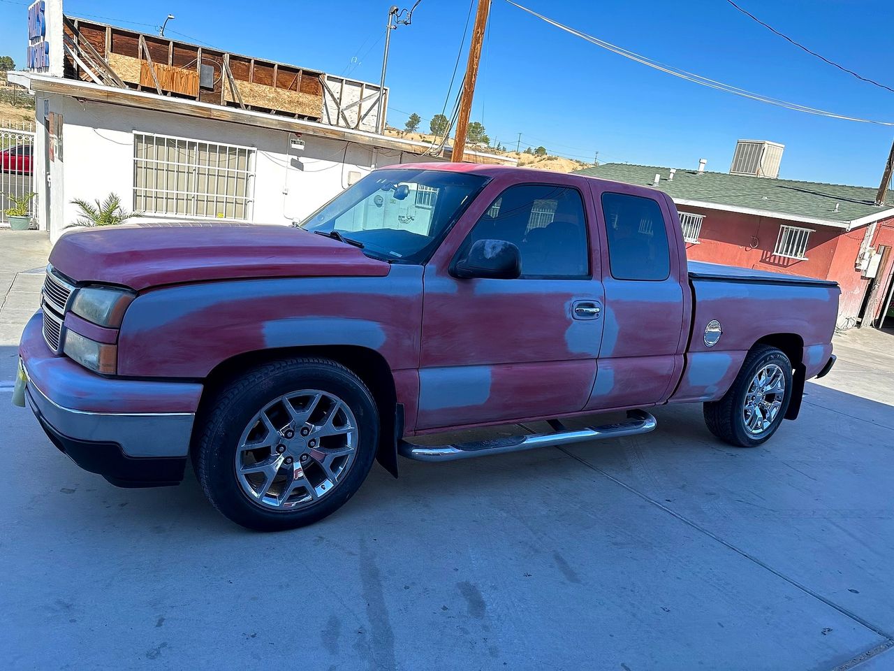 Red Chevy Silverado with gray primer patches on the hood, fender and doors