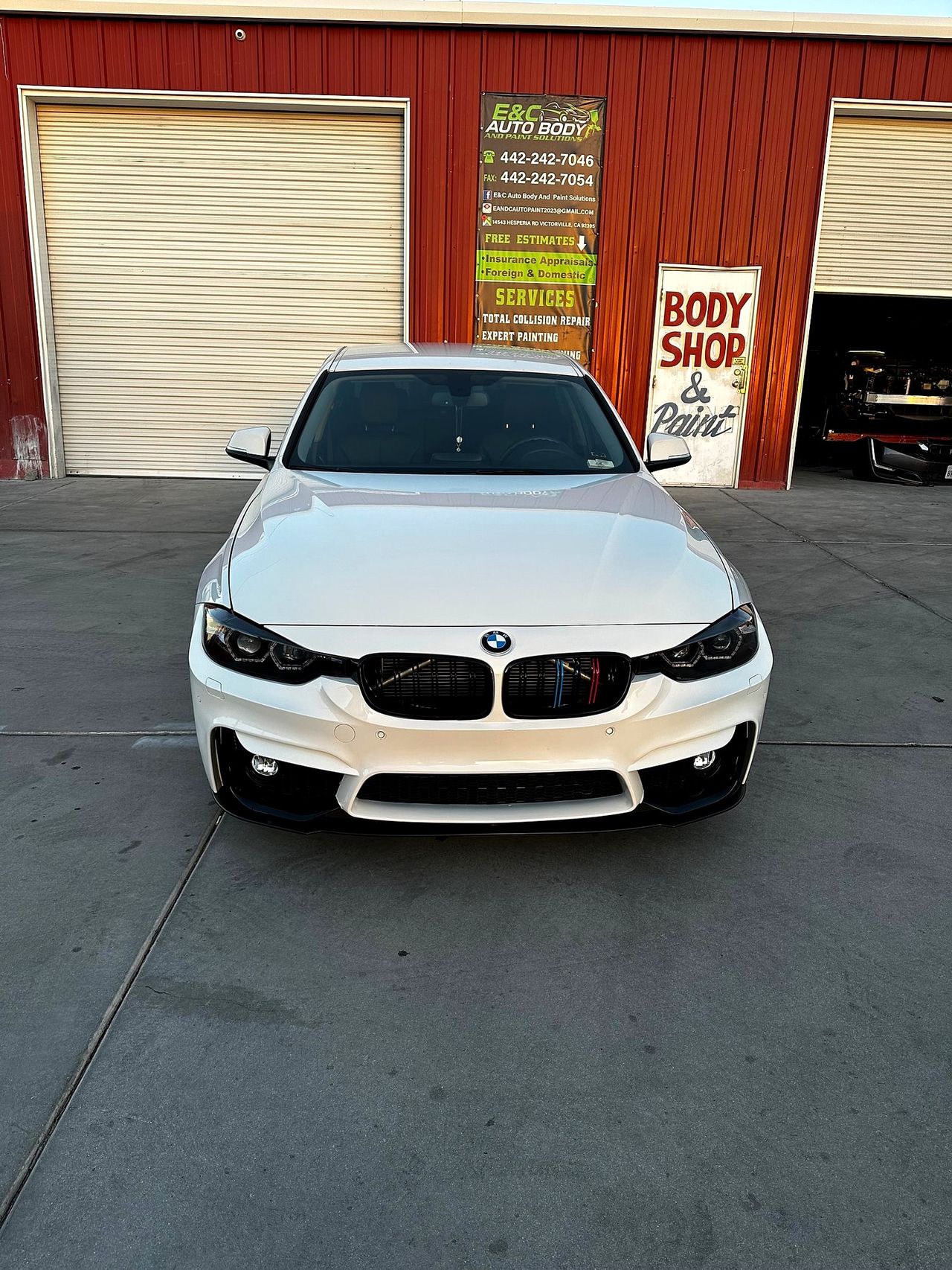White BMW 3 Series parked nose-on in front of the E&C banner